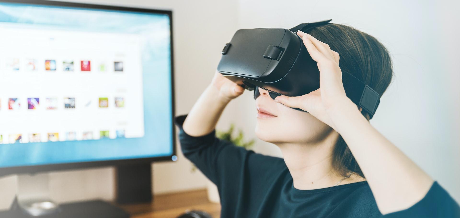 woman using black VR headset beside computer