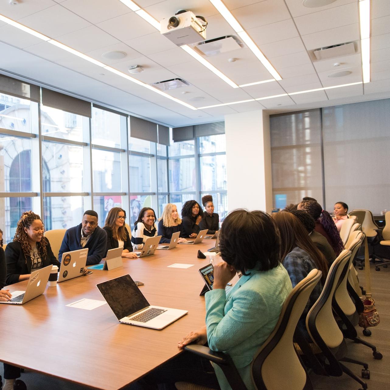 group of people sitting beside rectangular wooden table with laptops